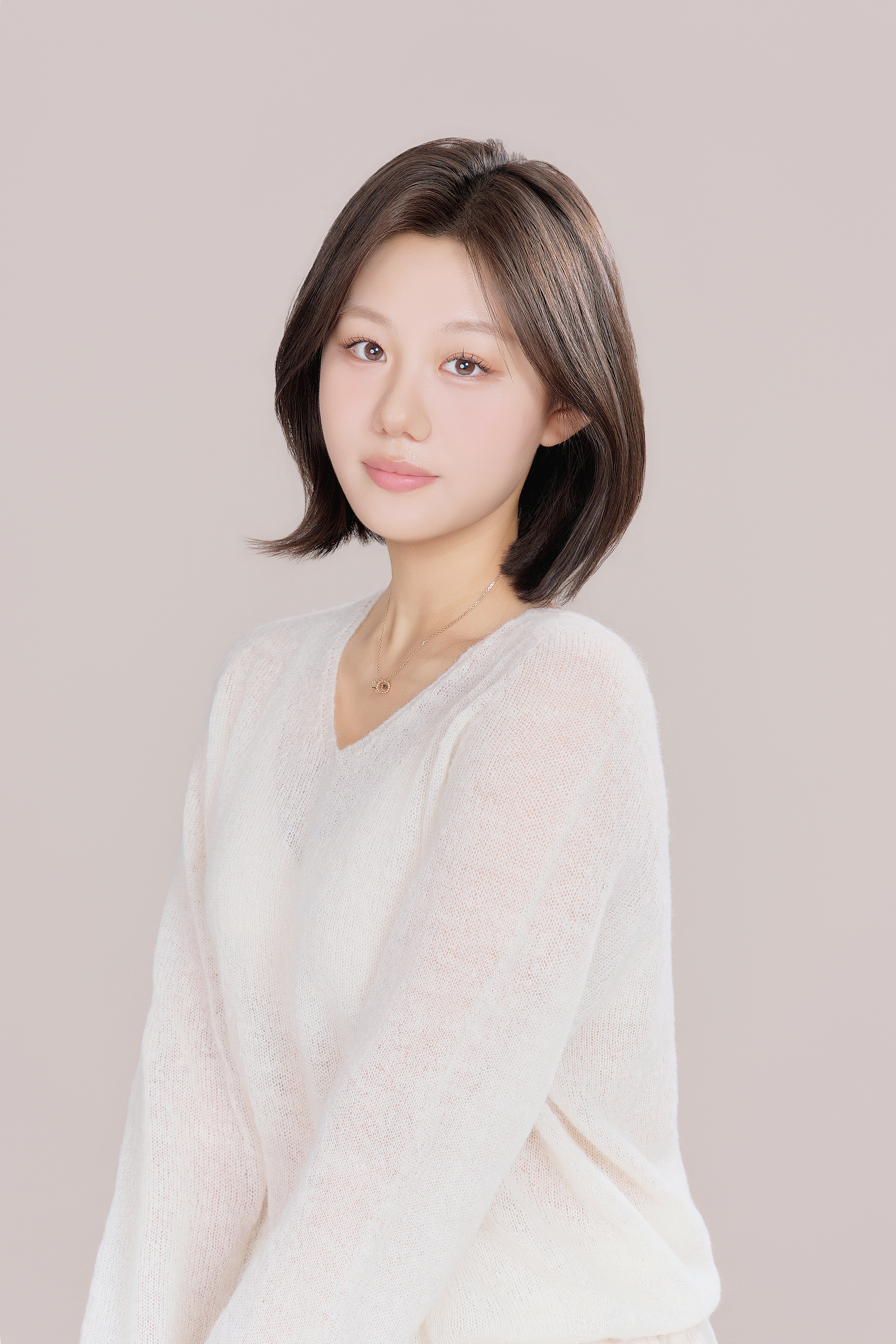연한 베이지 배경과 흰 니트로 촬영한 자연스러운 인물 프로필